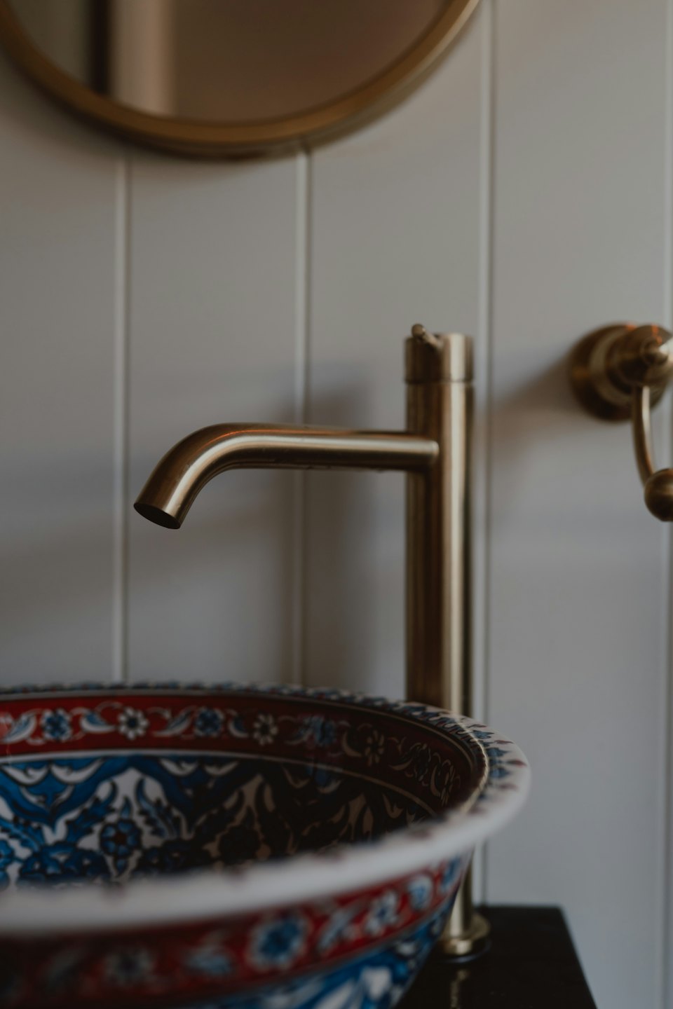 Accueil Robinet moderne en laiton brossé au-dessus d'un évier en céramique à motifs.