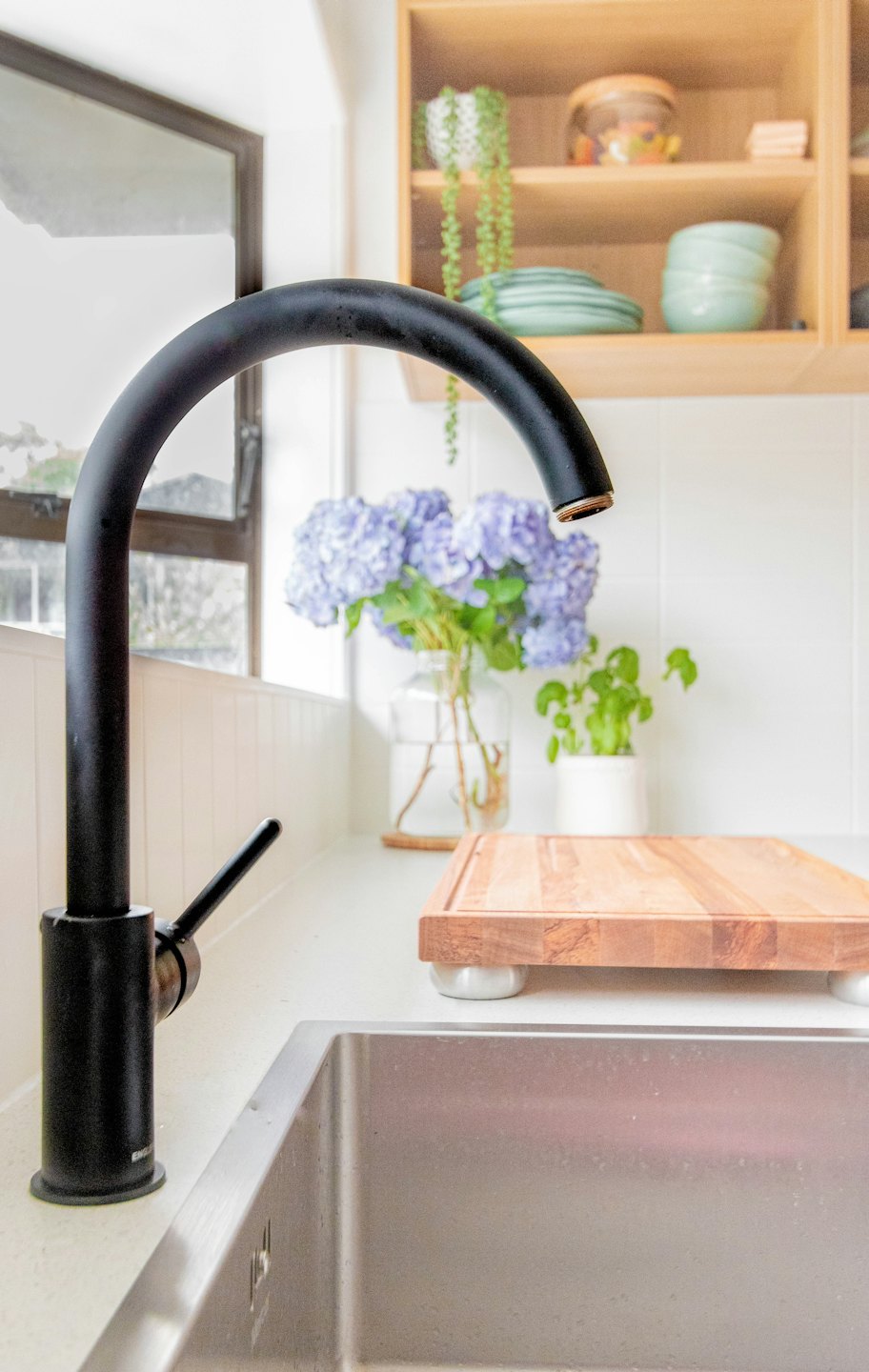 Accueil Évier de cuisine moderne avec robinet noir et hortensias violets.